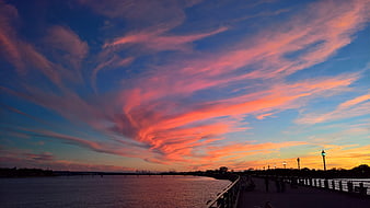 Vibrant Pink and Orange Sunset Sky Over River Promenade