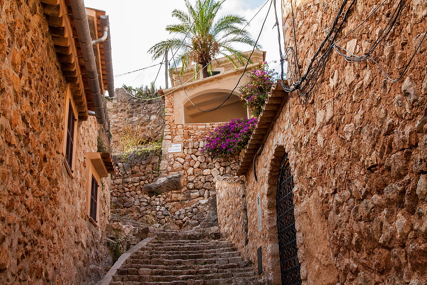 Narrow stone alleyway with stairs and bougainvillea flowers