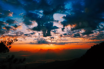 Dramatic Sunset Over Mountain Range with Silhouetted Trees