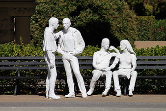 White statues of people on a park bench