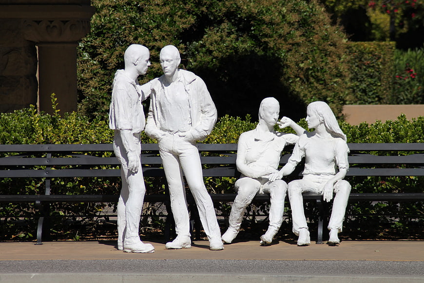 White statues of people on a park bench