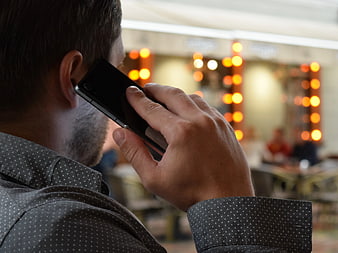 Man Talking on Smartphone in Blurred Cafe Background