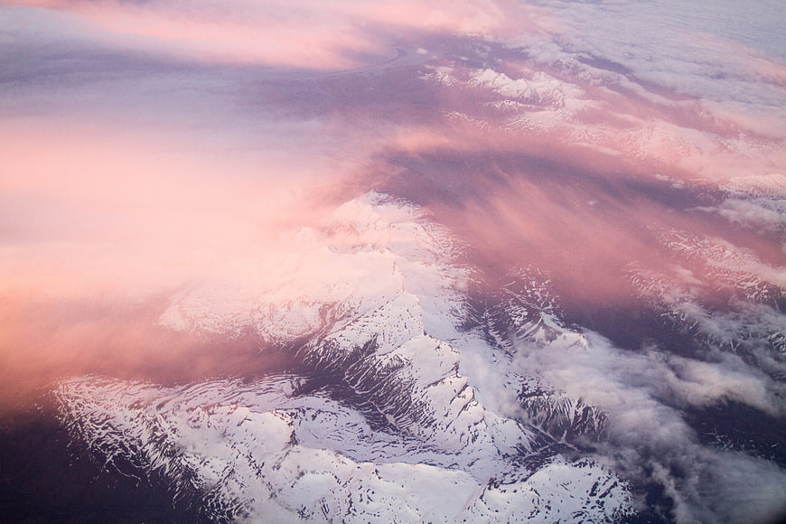Aerial View of Snowy Mountains with Pink Clouds