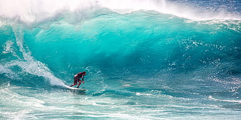 Surfer riding a massive turquoise wave barrel