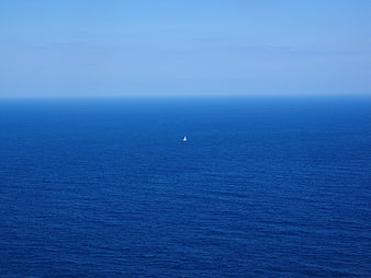 Lone Sailboat on Vast Blue Ocean Horizon