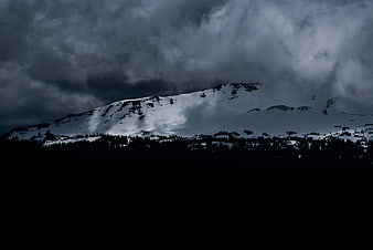 Dramatic Snow-Capped Mountain Peak Under Stormy Clouds
