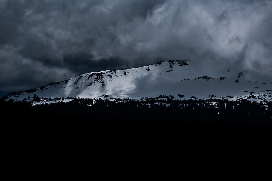 Dramatic Snow-Capped Mountain Peak Under Stormy Clouds