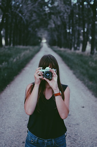 Woman photographer with vintage camera on forest path