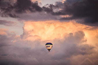 Hot Air Balloon Flying Against Dramatic Sunset Clouds