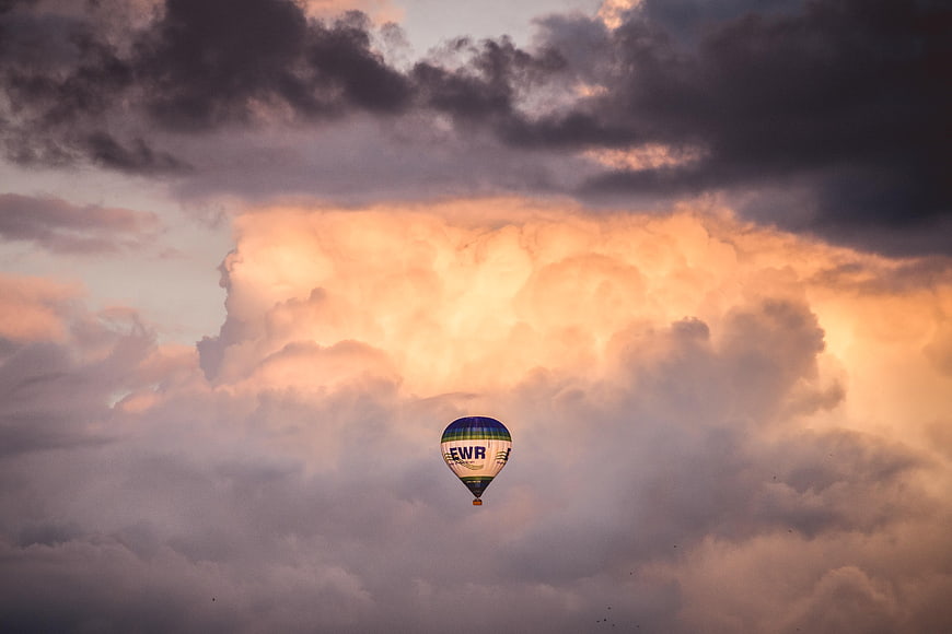 Hot Air Balloon Flying Against Dramatic Sunset Clouds