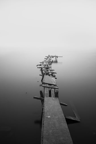 Decaying wooden pier disappearing into foggy water