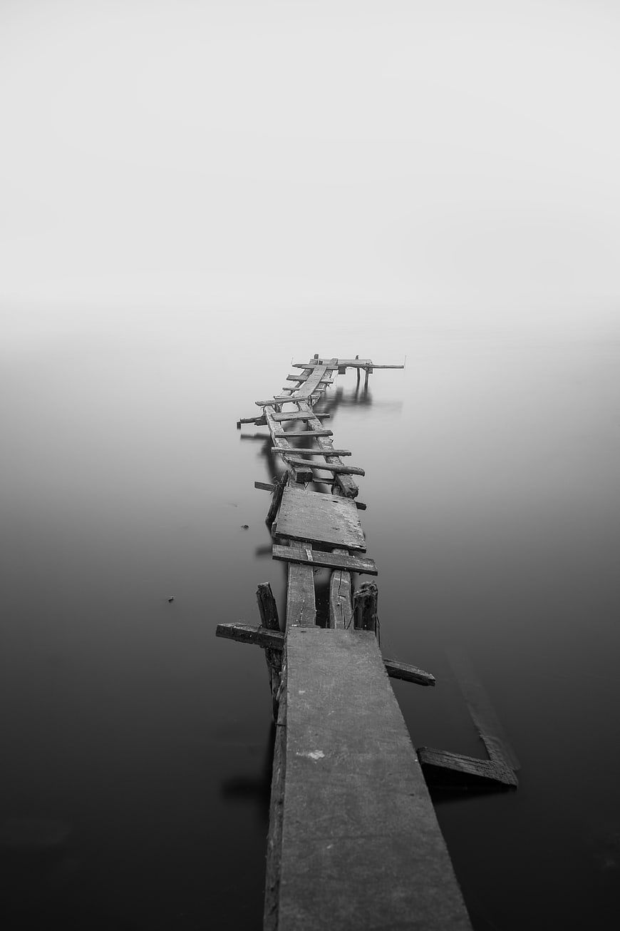 Decaying wooden pier disappearing into foggy water