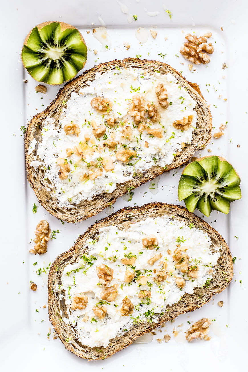 Ricotta toast with walnuts, kiwi, and lime zest on white