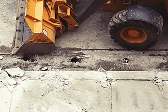 Yellow construction loader breaking concrete pavement