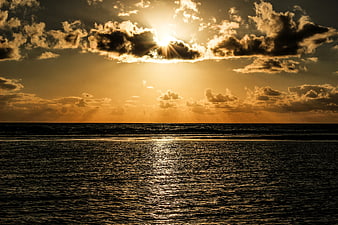 Dramatic Golden Sunset Over Ocean With Sun Rays Through Clouds