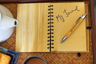 Open bamboo journal with wooden pen and coffee on woven mat