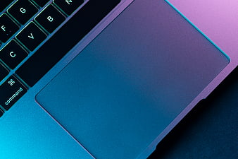 Close-up of laptop keyboard and trackpad with neon blue and purple lighting