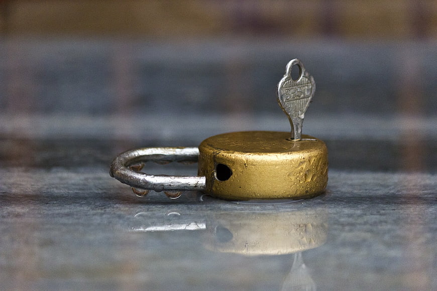 Vintage Brass Padlock With Key On Wet Stone Surface