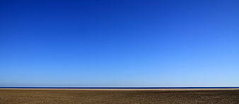 Minimalist Beach Landscape With Vast Blue Sky And Sandy Shore