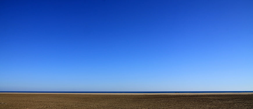 Minimalist Beach Landscape With Vast Blue Sky And Sandy Shore