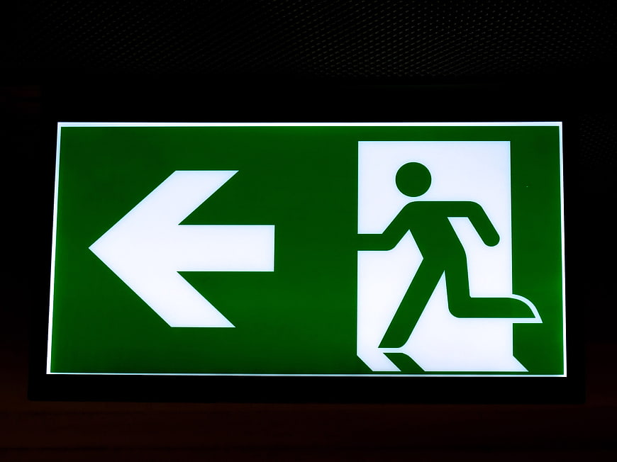 Illuminated green emergency exit sign with running man symbol