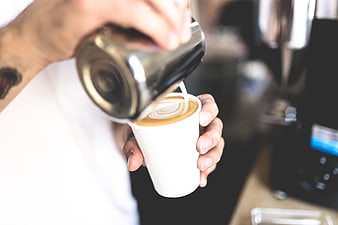 Barista Pouring Latte Art into White Coffee Cup