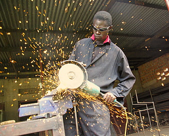 African worker using angle grinder with sparks flying
