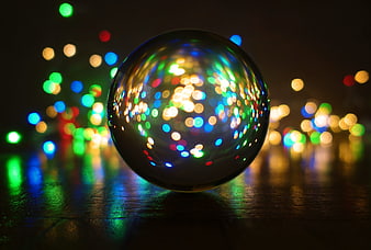 Crystal Ball Reflecting Colorful Bokeh Lights on Dark Wooden Surface
