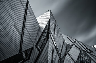 Low angle view of modern angular glass architecture against dark sky