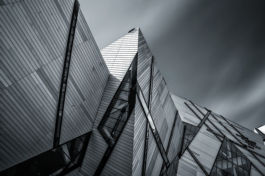 Low angle view of modern angular glass architecture against dark sky