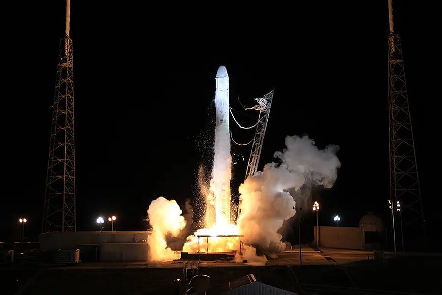 SpaceX Falcon 9 rocket launch at night with smoke and fire