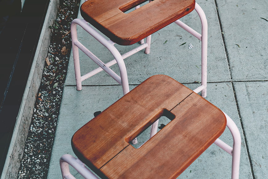 High Angle View of Wooden and Pink Metal Stools on Concrete