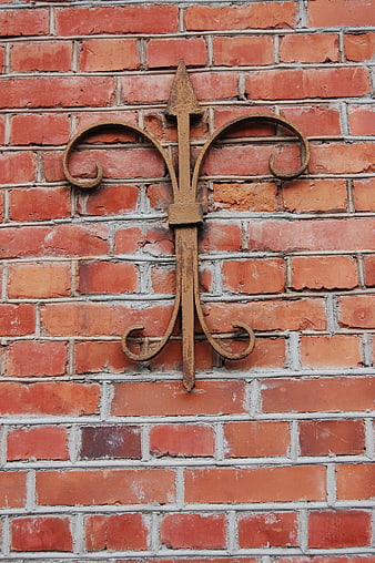 Rusty Wrought Iron Fleur-de-lis on Red Brick Wall