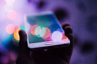 Hand holding smartphone with colorful bokeh lights