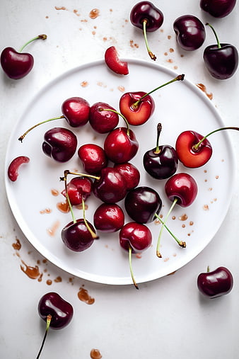 Fresh Red Cherries on White Plate with Syrup Splatters