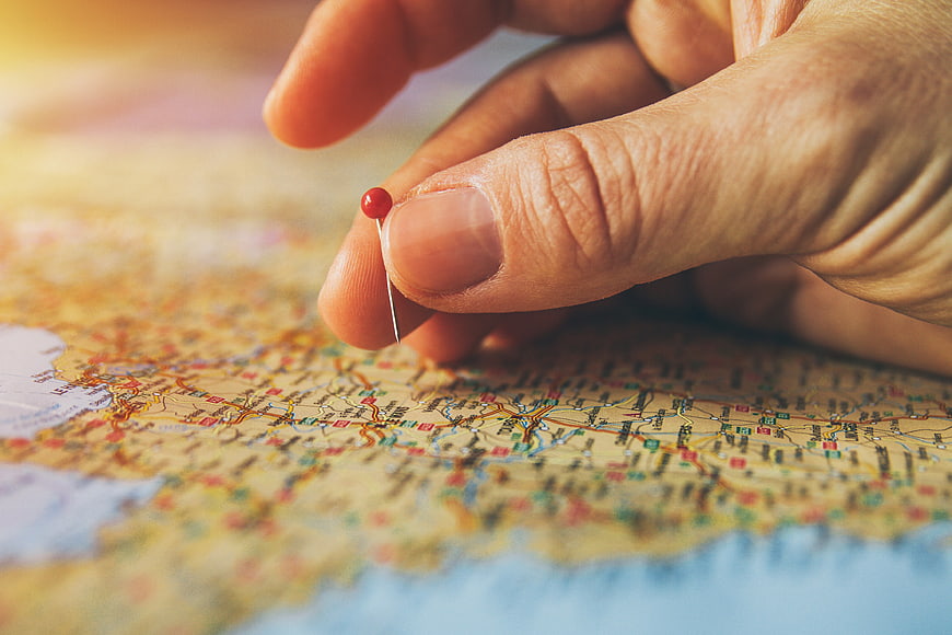 Hand Placing Red Pin on Travel Map