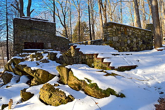 Snow-covered stone ruins in a winter forest landscape