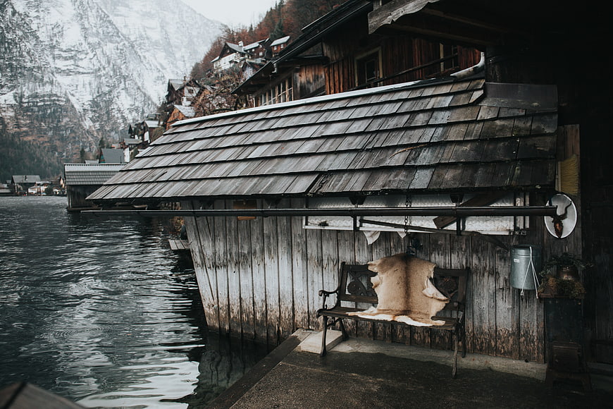 Rustic wooden boathouse on a lake with snowy mountains