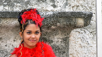 Young woman in red feathered costume against textured stone wall