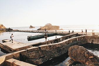 People walking on concrete structures at coastal beach