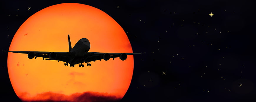 Airplane Silhouette Against Giant Orange Sun and Starry Night Sky