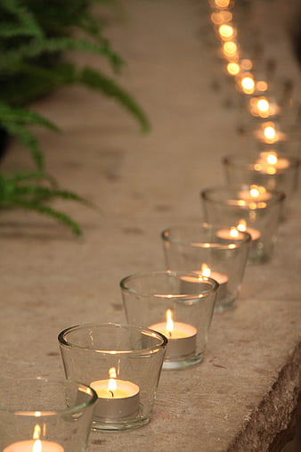 Row of lit tea light candles in glass holders on stone
