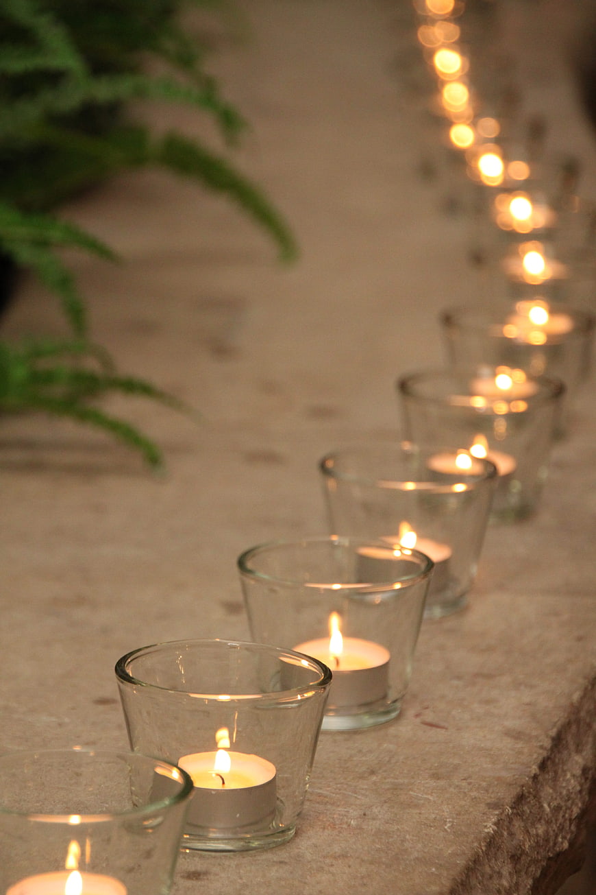 Row of lit tea light candles in glass holders on stone