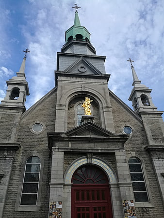 Low angle view of historic stone church facade with golden statue