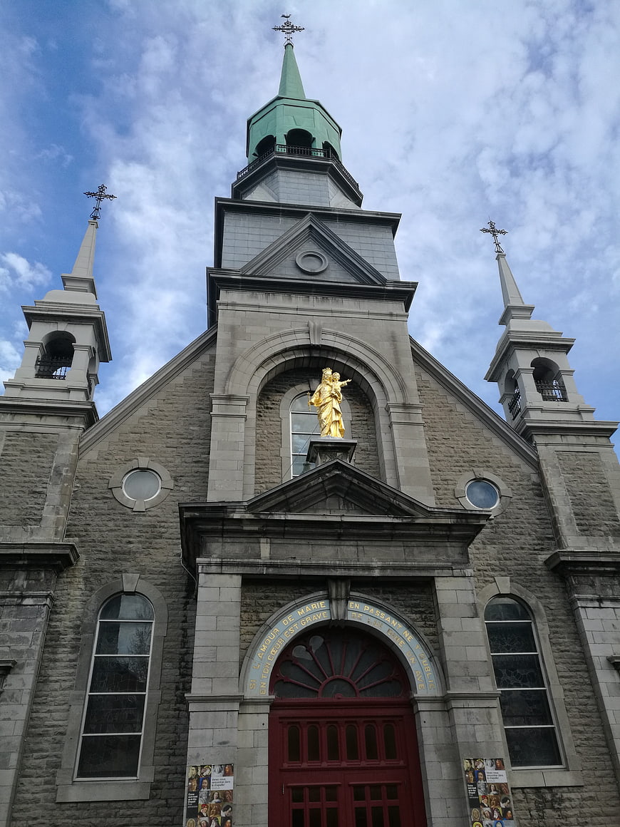 Low angle view of historic stone church facade with golden statue