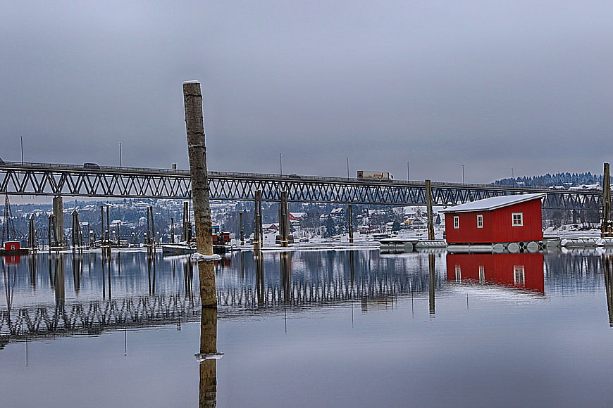 Red floating cabin reflected in calm winter harbor water