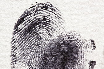 Close-up black ink fingerprint on textured white paper background