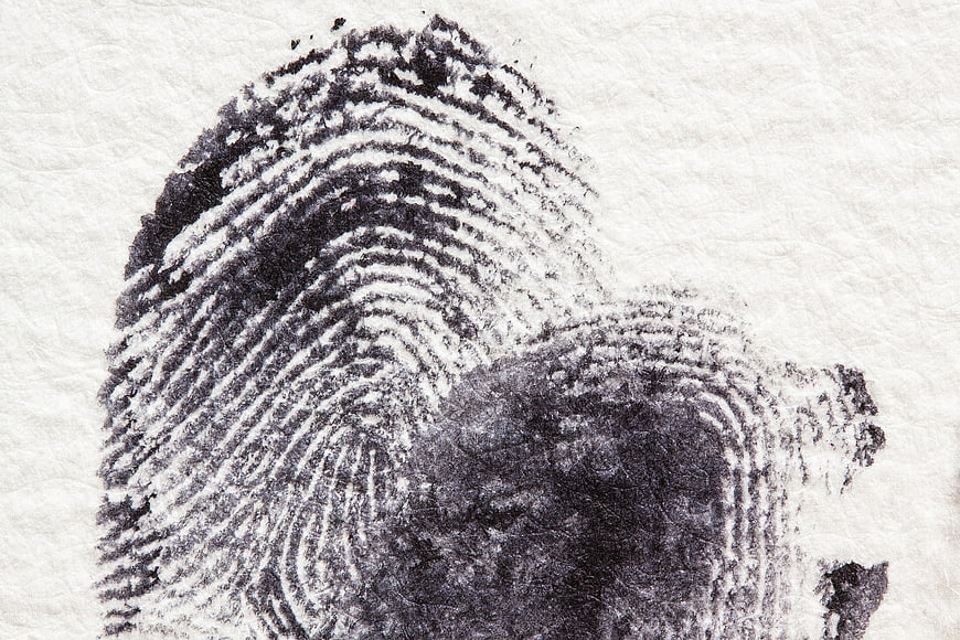 Close-up black ink fingerprint on textured white paper background