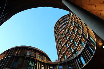 Low angle view of modern curved architecture against blue sky