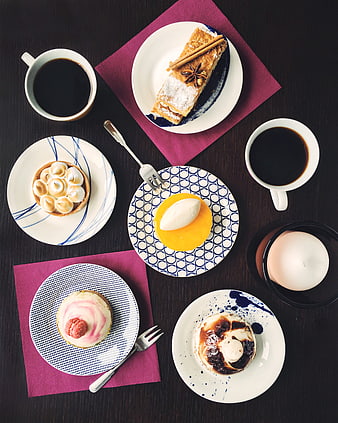 Overhead view of assorted desserts and coffee on dark table
